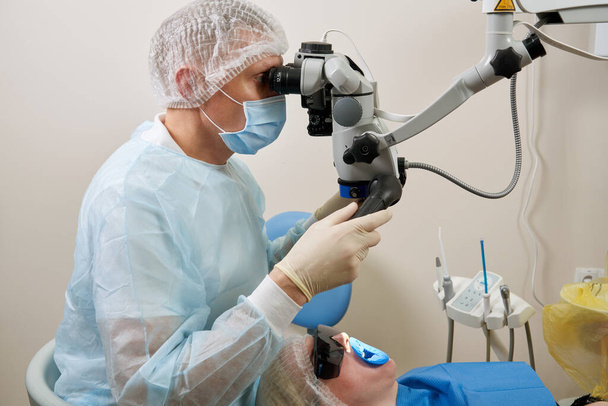 Dentist working with dental microscope and patient at modern dentist clinic - Foto, Imagem