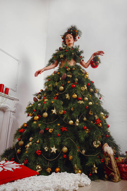 Krásná šťastná mladá dáma s vánoční borovice věnec na hlavě a módní vánoční stromeček šaty, zdobené vánoční koule, bobule a sněhové vločky. Nová koncepce roku - Fotografie, Obrázek