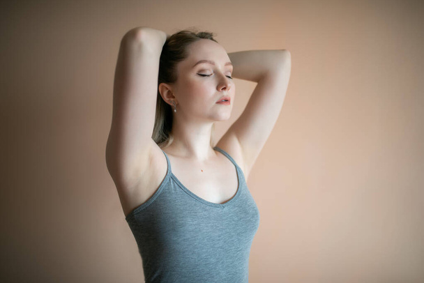 Graceful young woman posing against beige wall. - Photo, image
