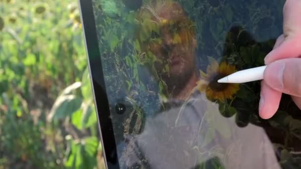 Bir adam ayçiçeği resimlerini çekmek için bir tablet kullanıyor. Hasatın durumunu internete kaydediyor.. - Video, Çekim
