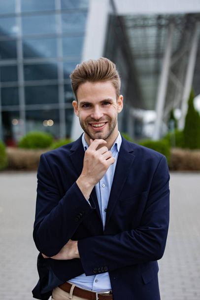 Portrait of handsome smiling man in casual wear. Successful young businessman.Young man standing on the city street near business center - Фото, изображение