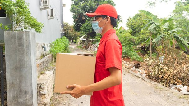 アジアの若者の配達で赤の制服を着たパッケージ - 写真・画像