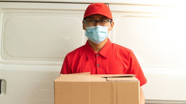 Asiatischer junger Mann in roter Uniform mit Paketen - Foto, Bild