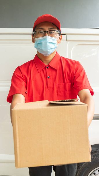 Asiatico giovane uomo consegna in uniforme rossa con pacchetti - Foto, immagini