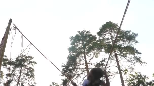Kleine Kinder springen auf dem Trampolin mit elastischen Seilen. Happy Boy fliegt in den Himmel. Baby Silhouette Jumping auf dem Trampolin Bungee Jumping. Kind im sicheren Gürtel springt hoch. Kindheitserinnerungen - Filmmaterial, Video