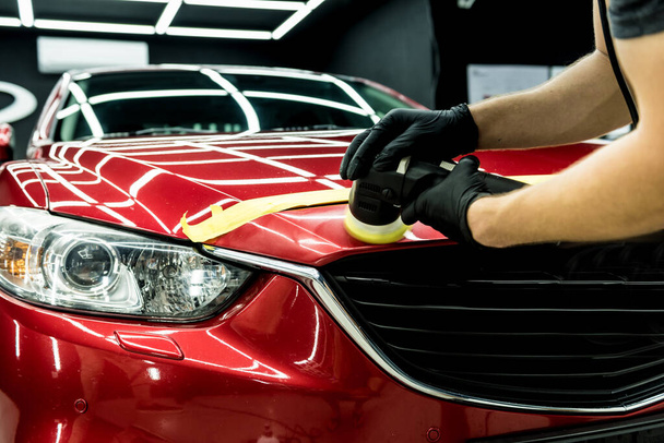 Car service worker polishes a car details with orbital polisher. - Foto, Bild
