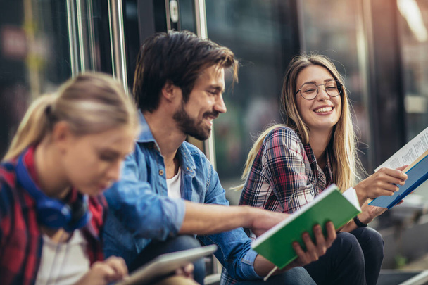 Szczęśliwi młodzi studenci studiujący książki na uniwersytecie - Zdjęcie, obraz