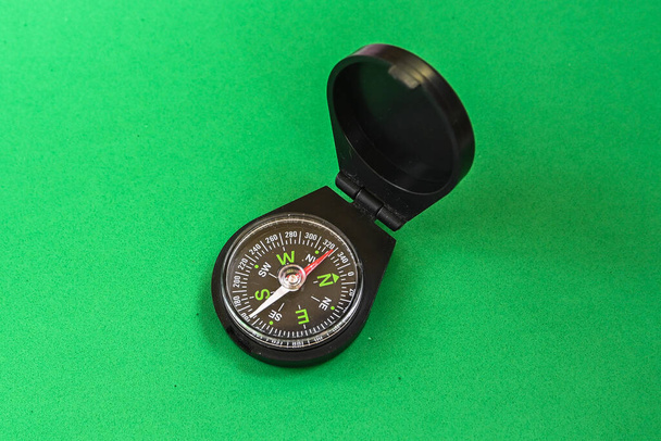 Компас на зеленому тлі. Магнітний компас, інструмент для навігації
. - Фото, зображення