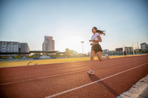 Asiatische junge Fitnessläuferin läuft auf Stadionbahn  - Foto, Bild