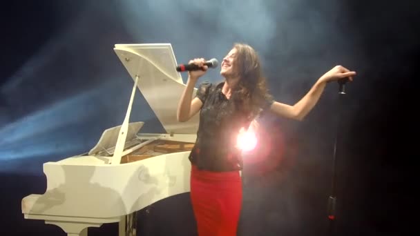 cantante con piano forte y micrófono realizando espectáculo vocal en el escenario con luz y humo, música. - Imágenes, Vídeo