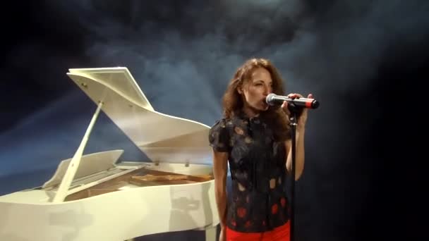 αισθησιακή γυναίκα τραγουδίστρια σε σέξι φορούν τραγούδι τραγούδι σε μικρόφωνο στο κλασικό λευκό πιάνο forte, φωνητικά. - Πλάνα, βίντεο