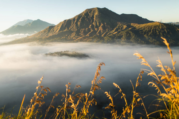 Sunrise view of mount Batur volcano in Bali from Pinggan village. Beautiful sunrise and low clouds. Panoramic view. - Photo, Image