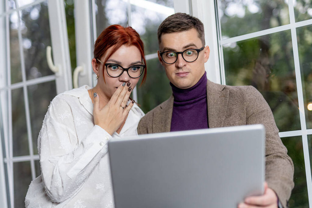 Business colleagues working on their break at the coffee shop. Man and woman are looking at screen with astonishment. Funny emotions. - Photo, image