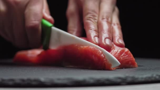 Sushi-Chef schneidet frischen Lachs an der Sushi-Bar. Chef schneidet Lachsfilet in professioneller Küche. Großaufnahme Koch Hände in Scheiben schneiden frischen Fisch in Zeitlupe. Professioneller Mann schneidet roten Fisch - Filmmaterial, Video
