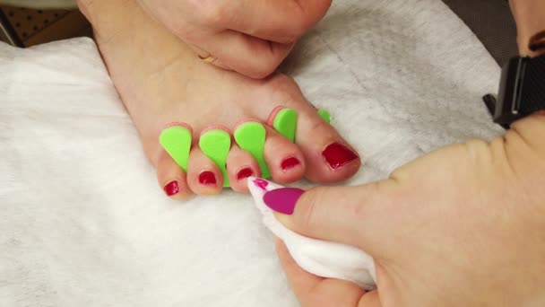 Nahaufnahme weiblicher Füße, die roten Nagellack lackieren, selbstgemachte Pediküre zu Hause. - Filmmaterial, Video