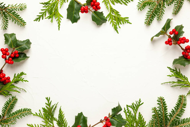Christmas background with branches of fir tree, evergreens and holly with red berries on white. Winter nature concept. Flat lay, copy space. - Foto, Bild