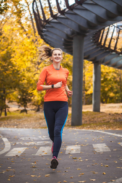 woman athlete on a morning jog in the autumn city park - Photo, Image
