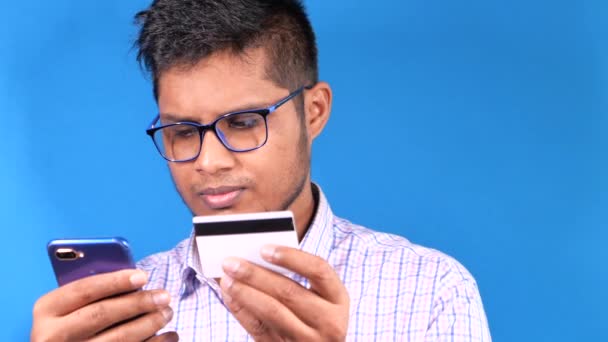 Мужчина держит в руках кредитную карту и пользуется смартфоном для покупок онлайн  - Кадры, видео