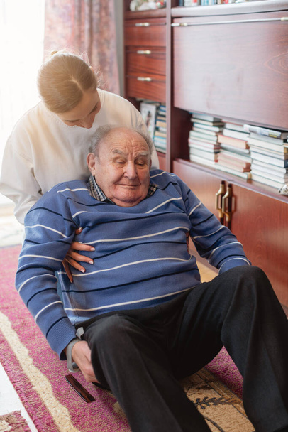Enfermera ayudando a un hombre mayor a levantarse después de caer - Foto, imagen
