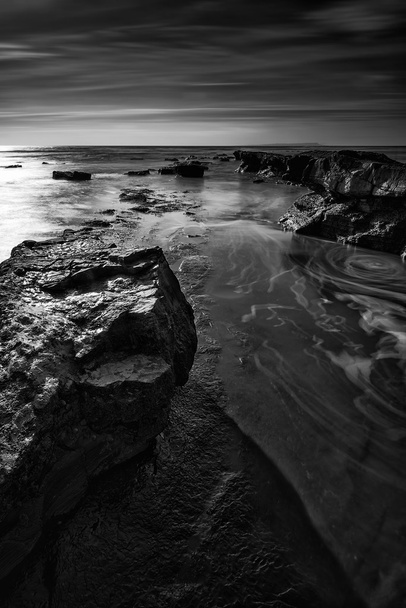 Beautiful black and white landscape of rocky shore at sunset - Photo, Image