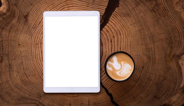 A white tablet with an empty screen and a Cup of coffee on a wooden table. - Zdjęcie, obraz
