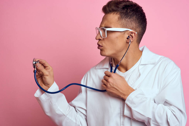 young doctor with a stethoscope and glasses on a pink background nurse interns model - Photo, image