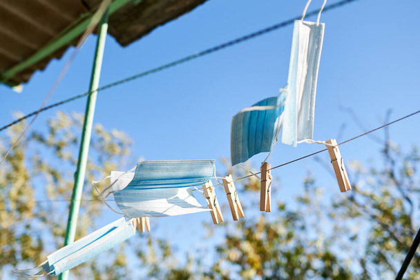 Zonovergoten gezichtsmaskers worden te drogen opgehangen voor desinfectie met houten wasknijpers. Nieuw normaal concept - Foto, afbeelding