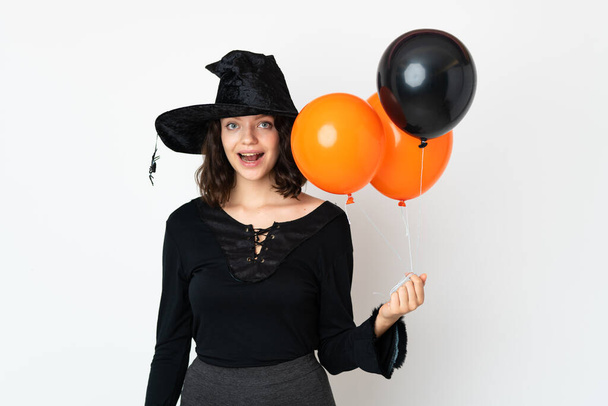 Bruxa jovem segurando balões de ar preto e laranja com expressão facial surpresa - Foto, Imagem