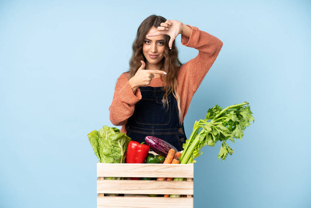 Farmer with freshly picked vegetables in a box focusing face. Framing symbol - Fotoğraf, Görsel
