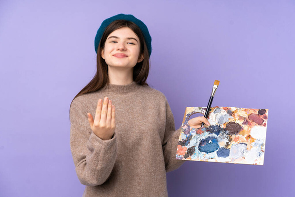 Ukrainan nuori taiteilija tyttö tilalla paletti yli eristetty violetti tausta kutsuva tulla käsin. Olen iloinen, että tulit. - Valokuva, kuva