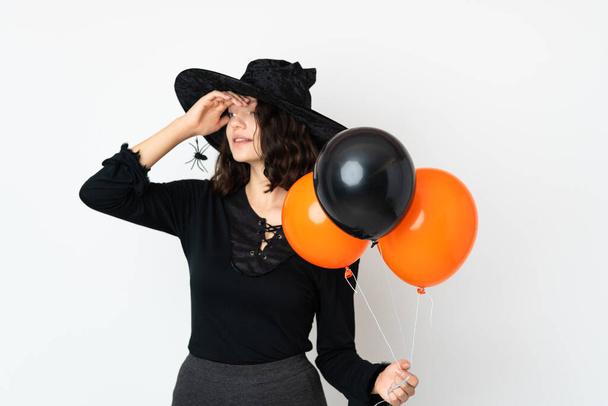Young witch holding black and orange air balloons has realized something and intending the solution - Foto, afbeelding
