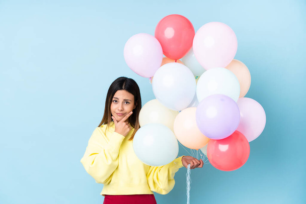 vrouw houden ballonnen in een partij over geïsoleerde blauwe achtergrond denken een idee - Foto, afbeelding