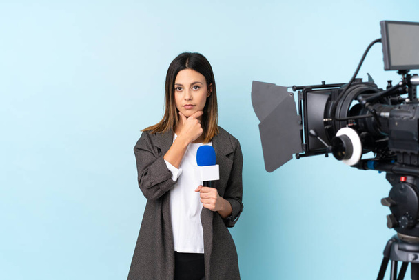 Reporterin hält ein Mikrofon in der Hand und berichtet Nachrichten über isolierten blauen Hintergrund und denkt eine Idee nach - Foto, Bild