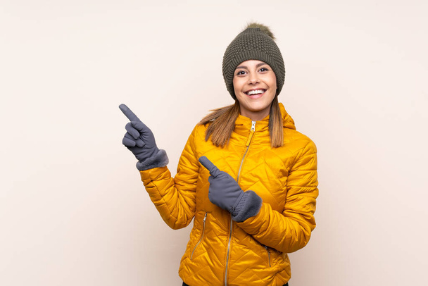 Femme avec chapeau d'hiver sur fond isolé pointant du doigt sur le côté - Photo, image