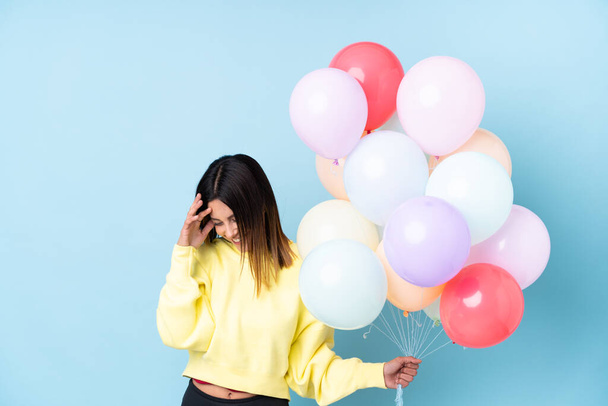 Woman holding balloons in a party over isolated blue background laughing - Fotografie, Obrázek