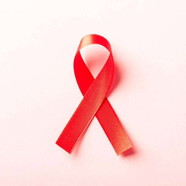Red bow ribbon symbol HIV, AIDS cancer awareness with shadows, studio shot isolated on pink background, Healthcare medicine concept, World AIDS Day - Foto, immagini