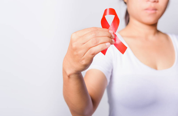 Closeup of female with red ribbon HIV AIDS on hand, World AIDS Day and medicine concept - 写真・画像
