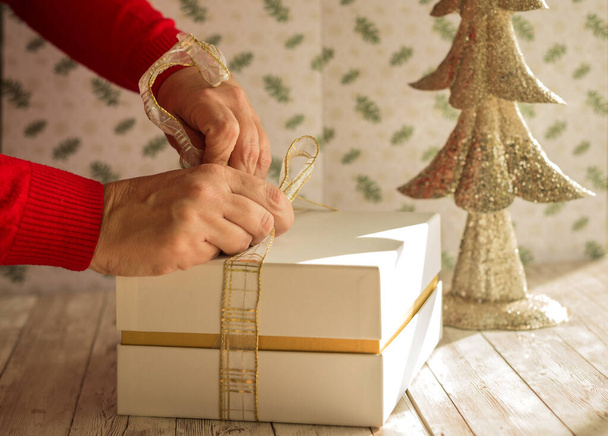 The packaging of a Christmas gift on a wooden table - Foto, imagen