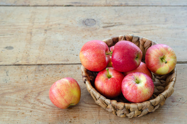 Le mele rosse sono nel cesto sul tavolo di legno, da vicino - Foto, immagini