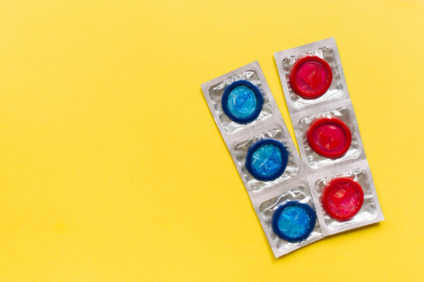 Composition with colorful condoms on yellow background. Safe sex and contraceptive concept. Flat lay, top view, copy space. - Photo, Image