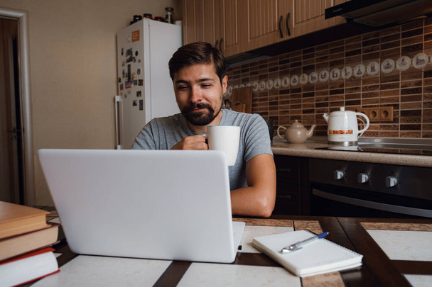 Portret szczęśliwego mężczyzny pijącego kawę w kuchni. Facet pracuje w domu.. - Zdjęcie, obraz