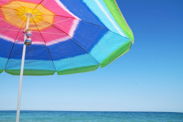 plážový deštník, pareo a sluneční brýle proti mořskému obzoru a čisté obloze, kopírovat prostor - Fotografie, Obrázek