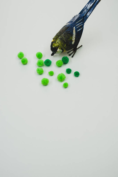 A vertical shot of a small handmade bird figure with green cotton balls isolated on a gray background - Foto, afbeelding