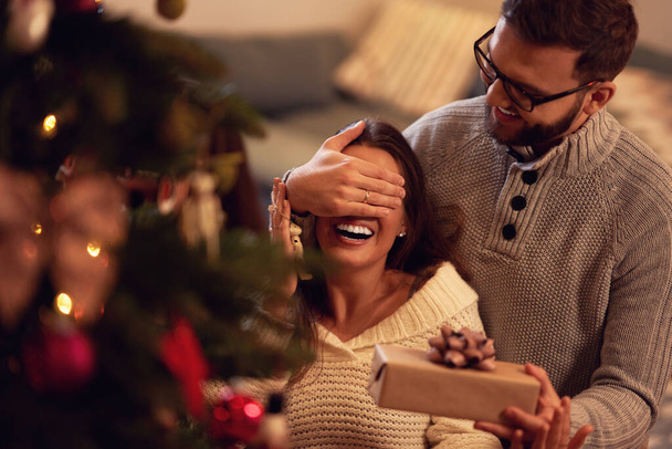 Pareja adulta con regalo sobre árbol de Navidad - Foto, imagen