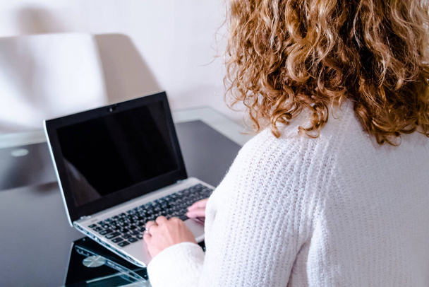 A woman with curly hair working with a laptop - Foto, Bild
