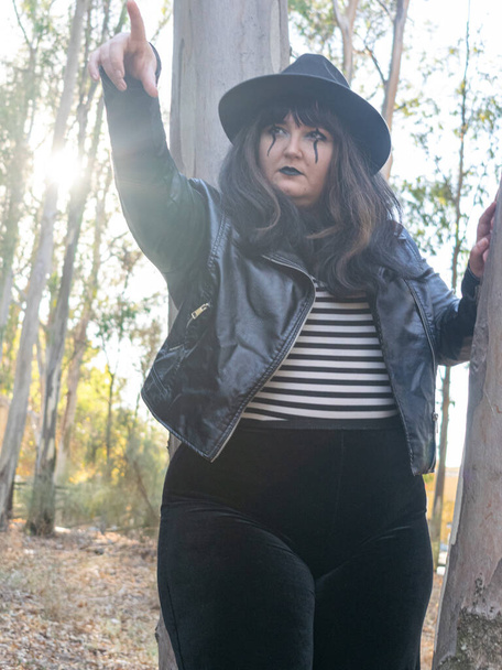 A shallow focus shot of a white fat female posing disguised for the Halloween in a forest - Photo, image