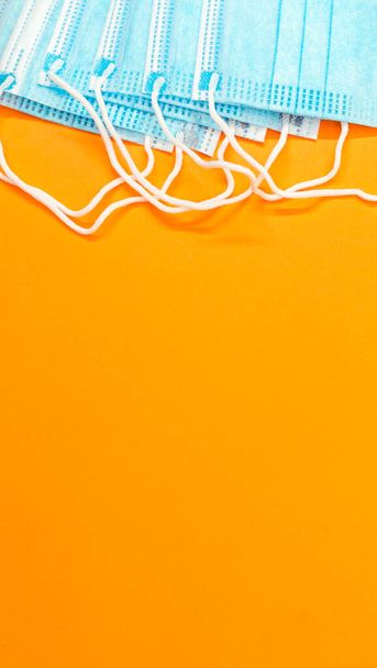 A vertical shot of surgical masks on an orange surface - Photo, image