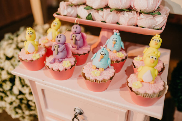 A high angle shot of cupcakes decorated with chick characters on a festive table - Photo, Image