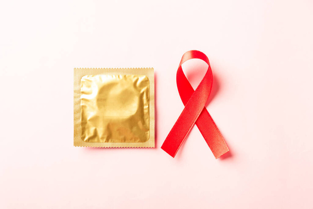 Red bow ribbon symbol HIV, AIDS cancer awareness and condom with shadows, studio shot isolated on pink background, Healthcare medicine sexually concept, World AIDS Day - Valokuva, kuva