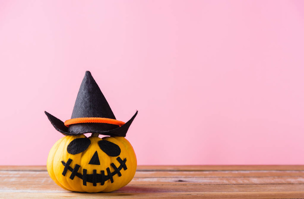 Funny Halloween day decoration party, closeup halloween pumpkin head jack o lantern smile scary on wooden and copy space, studio shot isolated pink background, Happy holiday concept - Photo, Image